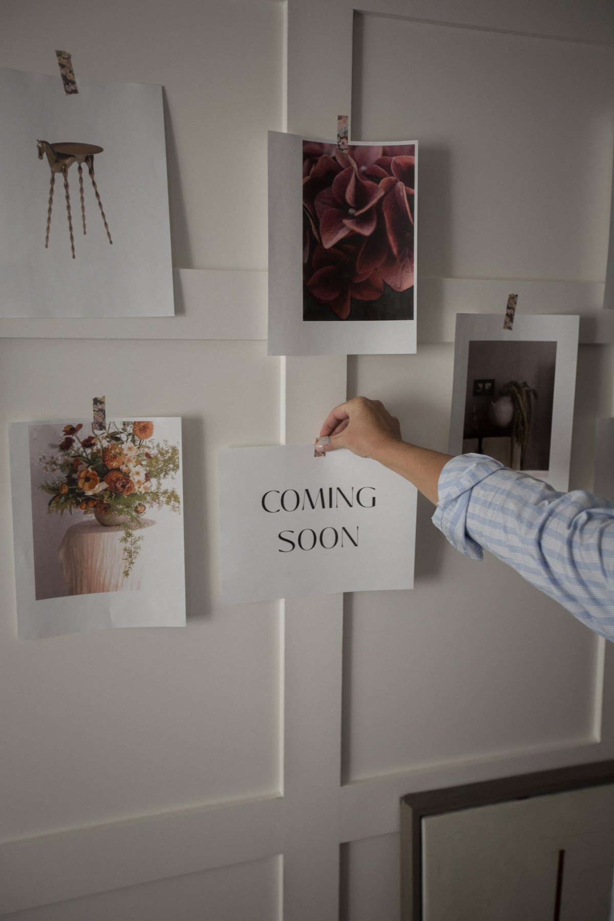 A hand pinning a card to a moodboard wall of fabric swatches and tear sheets