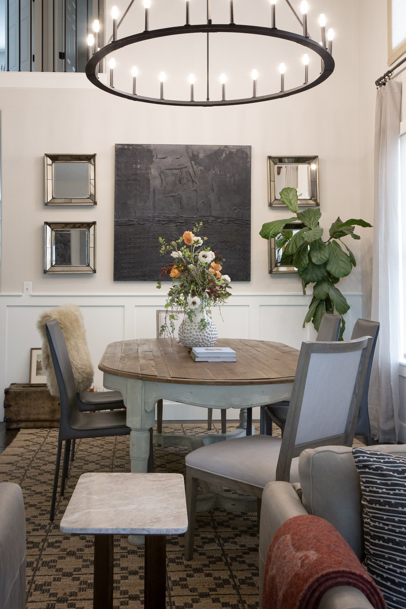 The same dining area seen upright, with a textured white vase of orange and white flowers on the table