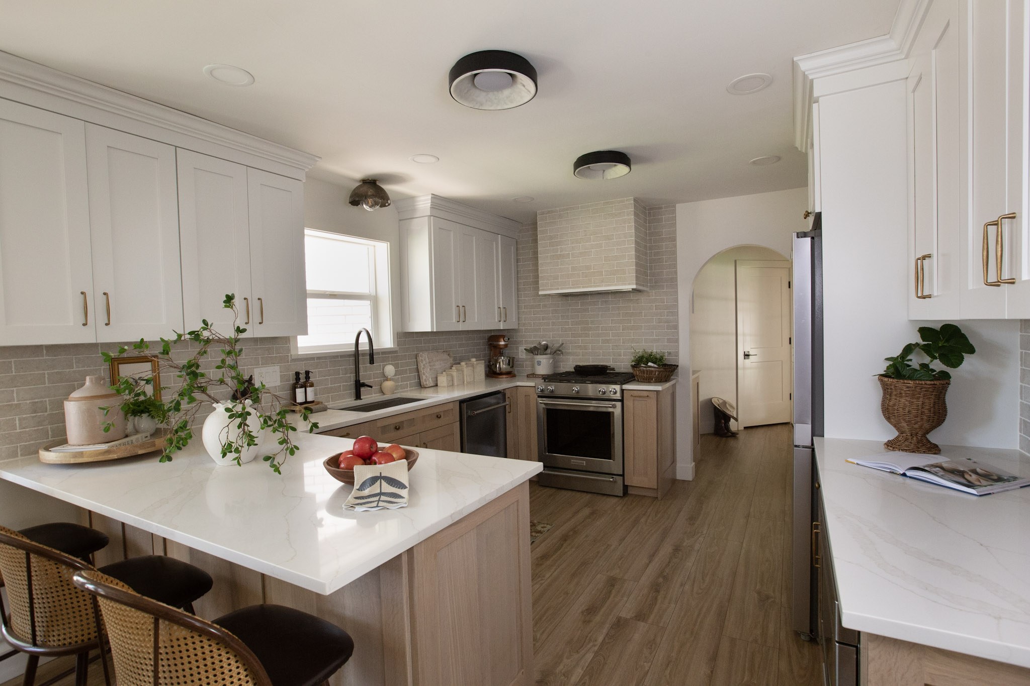 A wider view of the kitchen showing the range wall, styled counter, and a pale pink crock on a wooden tray